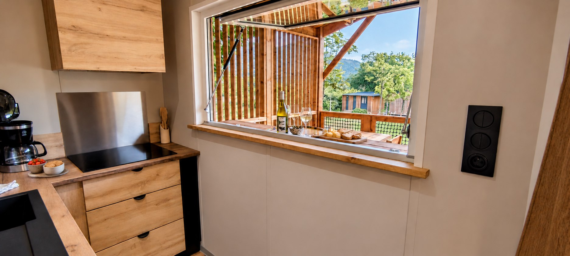 Depuis la cuisine, le comptoir ouvert sur la terrasse et les arbres